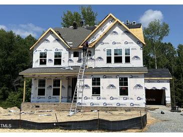 New construction home featuring a covered porch, large windows, and a two-car garage at 386 Rising Star Dr, Clayton, NC 27520