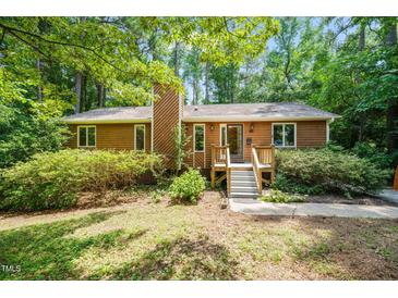 Charming single-story home with wood siding and a cozy front porch surrounded by mature trees and lush landscaping at 601 Wofford Rd, Durham, NC 27707