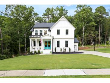 Charming two-story home with a bright blue front door, covered porch, and beautifully landscaped front yard at 720 The Parks Dr, Pittsboro, NC 27312