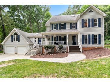 Traditional two-story home featuring neutral siding, dark shutters, covered porch, and mature landscaping at 11619 Appaloosa W Run, Raleigh, NC 27613
