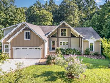 Charming exterior of home with manicured lawn, flowering bushes, two-car garage and beautiful architectural features at 136 Vireo Ln, Hillsborough, NC 27278