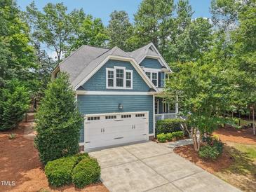 Charming blue two-story home featuring a two-car garage, manicured landscaping, and a welcoming front porch at 1419 Endgame Ct, Wake Forest, NC 27587