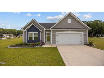 Charming single-story home with gray siding, a two-car garage and a well-manicured lawn with flower beds at 19 Linda Lou Ln # 19, Angier, NC 27501
