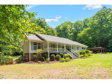 Charming single-story home featuring a welcoming front porch and beautifully landscaped yard surrounded by mature trees at 211 Hills Of The Haw Rd, Pittsboro, NC 27312