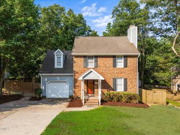 Charming brick home featuring a well-maintained lawn and inviting orange front door at 2205 Bufflehead Rd, Raleigh, NC 27616
