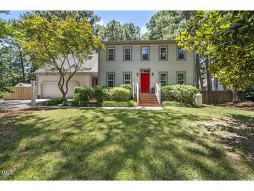 Traditional two-story home with a red front door, attached garage, and a well-manicured lawn and landscaping at 2704 Farnborough Rd, Raleigh, NC 27613