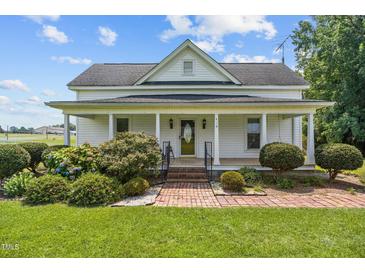 Charming home with a covered front porch, beautiful landscaping, and brick pathway leading to the entrance at 419 Mabry Rd, Angier, NC 27501