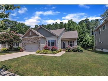 Charming single-story home with stone accents, a manicured lawn, and vibrant flower beds under a beautiful sky at 601 Minerva Dale Dr, Fuquay Varina, NC 27526
