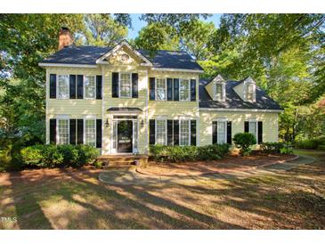 Charming yellow two-story home with black shutters surrounded by lush greenery and mature trees at 6201 King Croydon Ct Ct, Raleigh, NC 27603