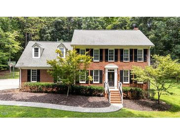 Charming red brick two-story home featuring classic black shutters and landscaped front yard at 10721 Marabou Ct, Raleigh, NC 27614