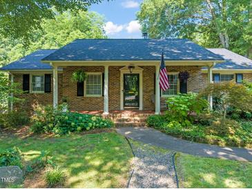 Charming brick home featuring a manicured front yard and inviting front porch with an American flag at 1311 Norton St, Durham, NC 27701