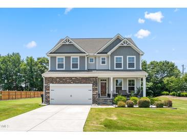 Beautiful two-story home featuring a stone and gray facade with a well-manicured lawn at 1321 White Spruce Dr, Willow Springs, NC 27592