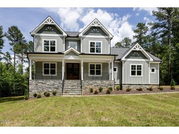 Charming home featuring stone accents, a welcoming front porch, and a beautifully landscaped yard at 200 Whistlers Cv, Louisburg, NC 27549