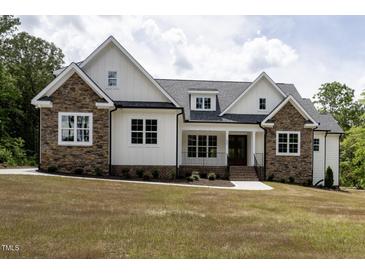 Beautiful home with stone and white siding, a covered porch, and professional landscaping at 225 Whistlers Cv, Louisburg, NC 27549