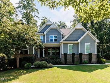 Charming two-story home featuring manicured lawn and mature trees on a sunny day at 354 Crimson Way, Pittsboro, NC 27312