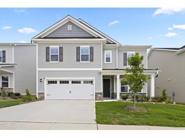 Charming two-story home with gray siding, stone accents, and a well-manicured lawn and a two car garage at 544 Tanner Lake Ln, Raleigh, NC 27610
