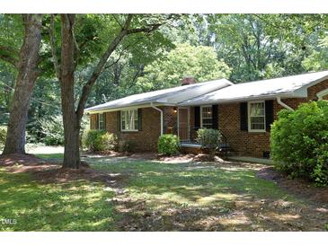 Charming brick home featuring a well-maintained lawn, classic shutters, and mature trees, offering a serene curb appeal at 1964 Wellington Rd, Burlington, NC 27217