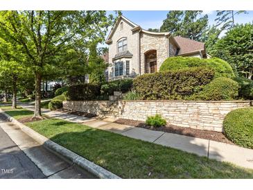 Elegant home featuring a light brick facade, lush landscaping, and a retaining wall at 3311 Canoe Brook Pkwy, Raleigh, NC 27614