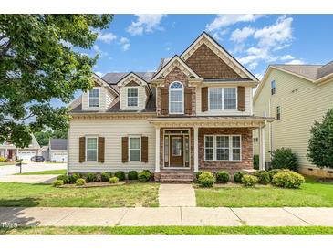 Inviting two-story home featuring stone accents, dormer windows, and a well-manicured front lawn at 410 Stranraer Ct, Fuquay Varina, NC 27526