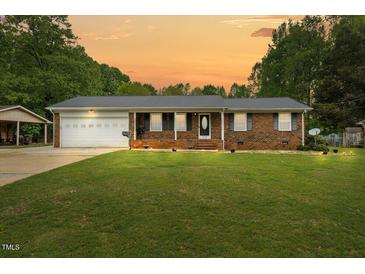 Charming brick home featuring a metal roof and well-manicured lawn at 410 W Tenth St, Siler City, NC 27344