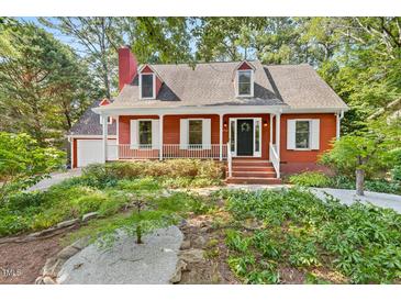 Charming red home with a front porch, white trim, and a well-maintained landscaped yard at 6728 Glen Forrest Dr, Chapel Hill, NC 27517