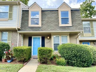 Charming townhome featuring a bright blue door, tidy landscaping, and dormer windows reflecting the sky at 4324 Halliwell Dr, Raleigh, NC 27606