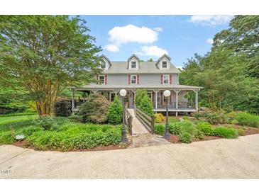 Charming two-story home features a covered porch, landscaped yard, and a picturesque bridge entrance at 53 Lake Wendell Rd, Wendell, NC 27591
