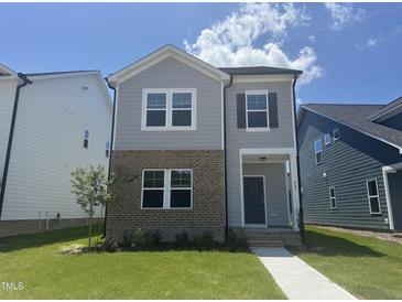 Charming two-story home with a combination of brick and siding on a beautiful lawn with a clear blue sky at 805 Portland Rose Dr, Knightdale, NC 27545