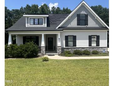 Charming home showcasing gray siding, black shutters, manicured lawn, and inviting front porch with stone accents at 820 Christian Light Rd, Fuquay Varina, NC 27526