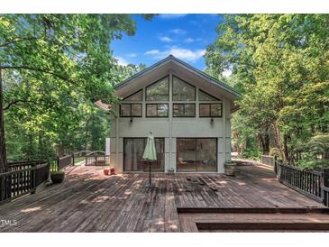 Modern home exterior featuring a spacious wooden deck and large windows, surrounded by lush trees at 8510 Dunlee Falls Rd, Raleigh, NC 27613