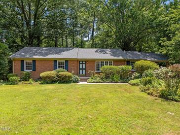 Charming brick home with a well-manicured lawn, mature trees, and lush landscaping at 111 Lattimore Ln, Durham, NC 27713