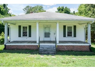 Charming single-story home featuring a covered front porch, white siding, and neatly trimmed dark green shutters at 310 Spring St, Durham, NC 27703