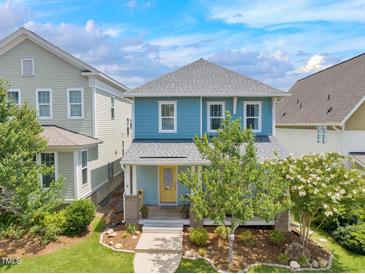 Charming two-story blue home with a yellow door, front porch, and landscaped front yard at 322 Tobacco Farm Way, Chapel Hill, NC 27516