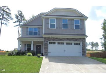 Charming two-story home with a well-manicured lawn, stone accents, and an attached two-car garage at 124 Richmond Run, Stem, NC 27581