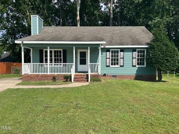 Charming home boasts a welcoming porch and well-manicured lawn, perfect for relaxing outdoors at 2012 Ranch Mill Cir, Raleigh, NC 27610