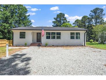 Charming renovated home with gravel drive, white painted brick, black roof and trim and lovely yard at 311 Troy St, Creedmoor, NC 27522