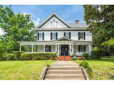 Charming two-story home with black shutters and a welcoming front porch, framed by lush greenery at 401 N Main St, Louisburg, NC 27549