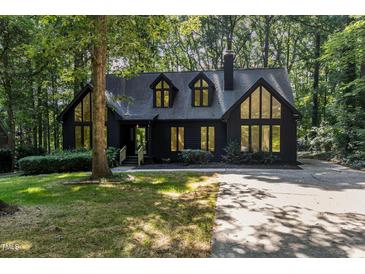 Charming exterior view of the home featuring large windows, a dark facade and mature trees at 5217 West Oaks Dr, Fuquay Varina, NC 27526