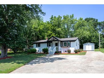 Charming home featuring a manicured lawn, lush landscaping, and a driveway leading to a detached storage shed at 1344 Highland Dr, Wake Forest, NC 27587