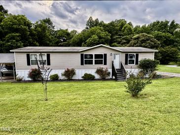 Charming single-story home with a well-maintained lawn, complemented by lush trees and a carport at 1404 N N Nc Hwy 87, Elon, NC 27244