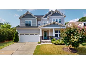 Charming two-story home with a well-manicured lawn, a turquoise front door, and a two-car garage at 1880 Woodall Crest Dr, Apex, NC 27502