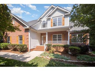 Charming two-story home featuring a brick and siding exterior, a front porch, and well-maintained landscaping at 2613 Sweet Gum Dr, Hillsborough, NC 27278