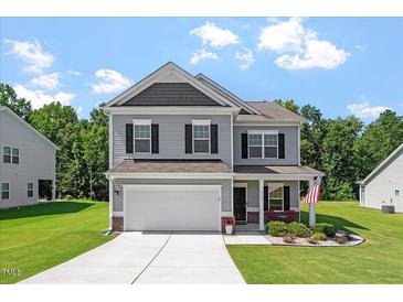 Charming two-story home featuring gray siding, black shutters, and a well-manicured lawn on a sunny day at 534 Lionheart Ln, Sanford, NC 27330