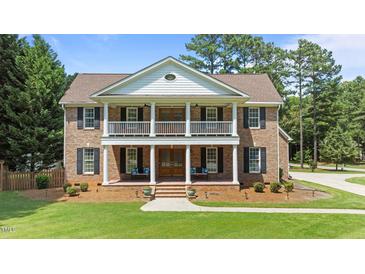 Two story brick home with manicured lawn, a symmetrical facade, and a welcoming front porch with seating at 55 Fleming Forest Dr, Youngsville, NC 27596