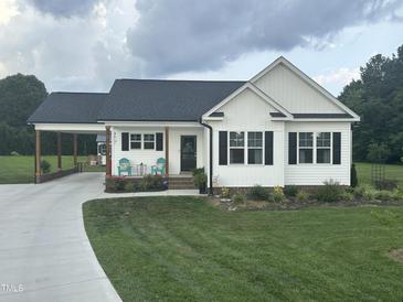 Charming one-story home featuring a landscaped front yard, covered driveway and cozy porch with seating at 8 Open View Ln, Timberlake, NC 27583