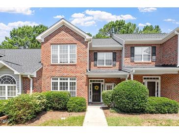 Charming brick townhome with a manicured lawn and a welcoming front door wreath at 1505 Poets Glade Dr, Apex, NC 27523
