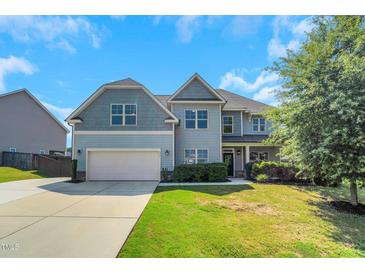 Charming two-story home with a two-car garage, manicured lawn and beautiful curb appeal under a blue sky at 315 Sugarpine Trl, Clayton, NC 27520