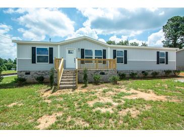 Charming single-story home featuring a light gray exterior, black shutters, and a welcoming front porch at 101 Cottonwood Ct, Kenly, NC 27542