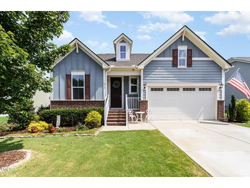 Charming two-story home with blue siding, brick accents, landscaped yard, and inviting front entrance at 210 Olde Liberty Dr, Youngsville, NC 27596