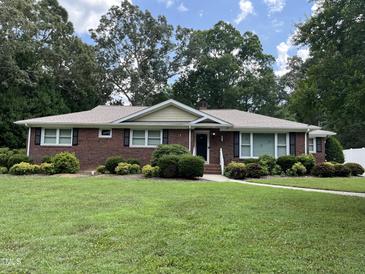 Charming brick home features mature landscaping, a well-manicured lawn, and inviting curb appeal at 211 Hillcrest Dr, Oxford, NC 27565